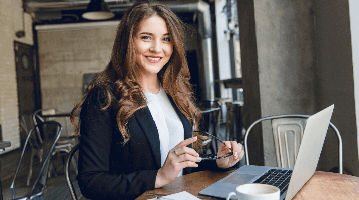 widely-smiling-businesswoman-working-laptop-sitting-cafe